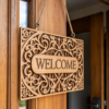 Custom laser engraved wooden welcome sign board hanging on a wooden door